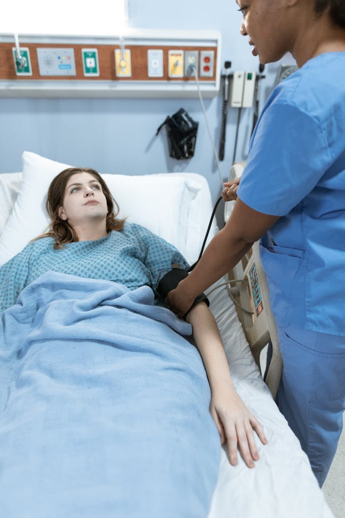A nurse in scrubs monitors a patients vitals in a hospital setting, providing healthcare care.
